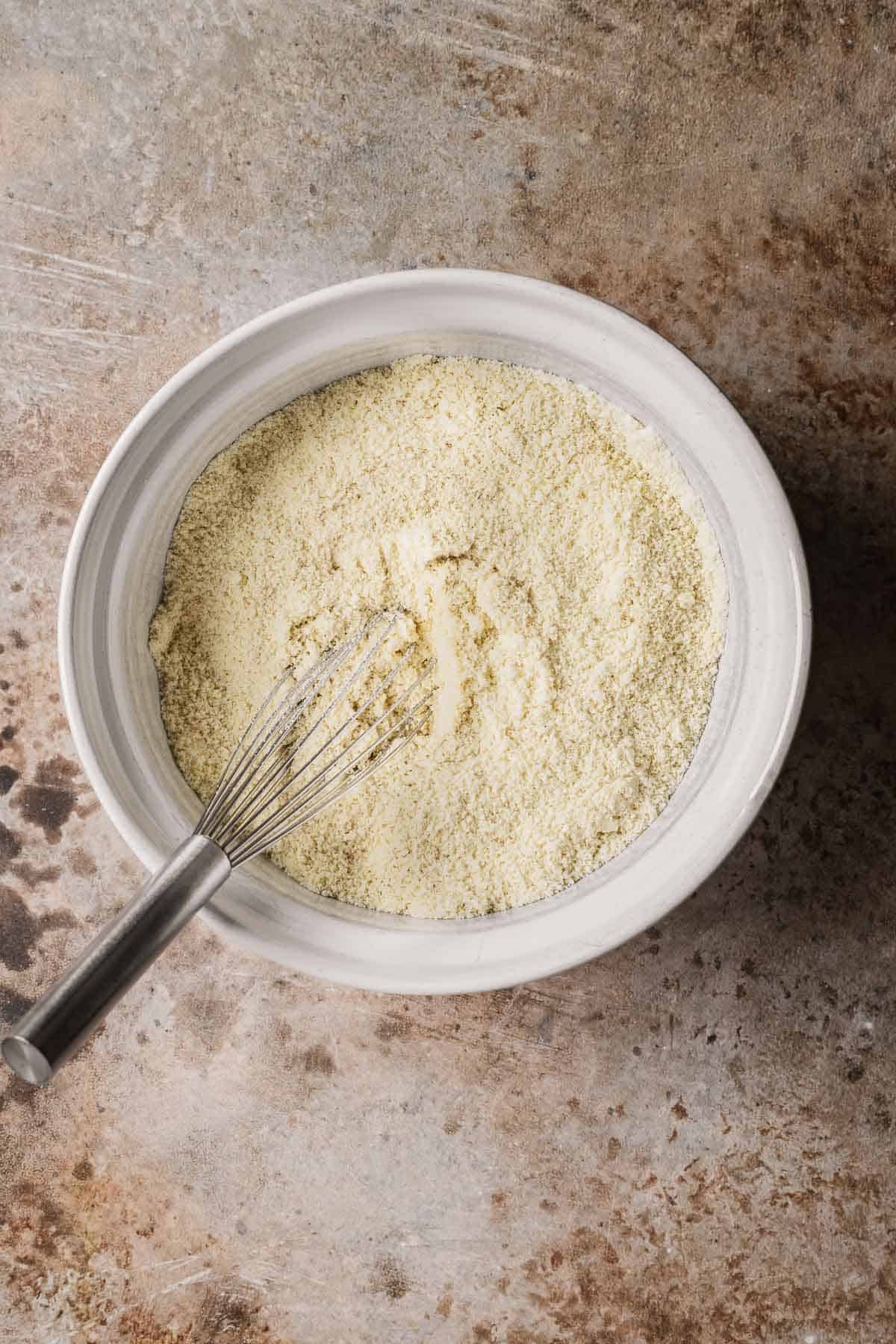 Almond flour and all purpose flour whisked together in a white ceramic bowl.