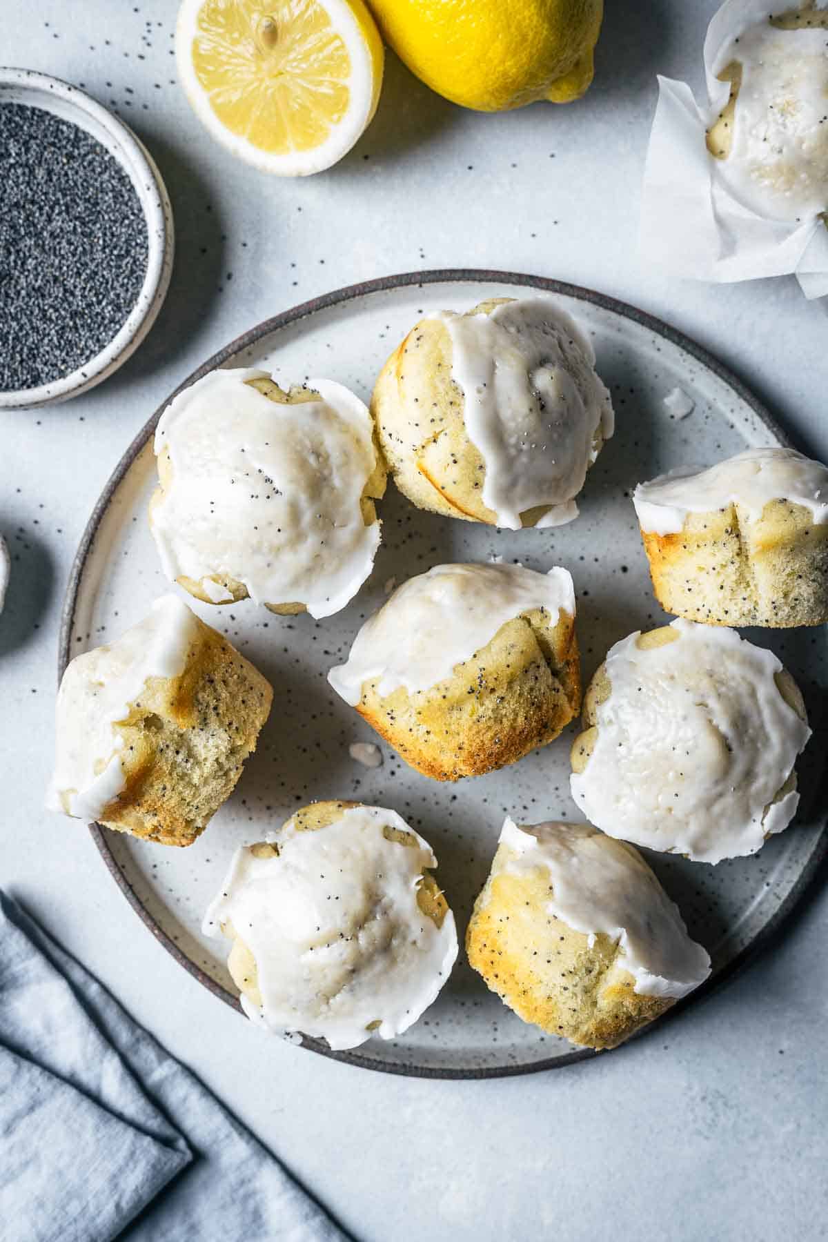 Glazed lemon poppy seed muffins on a speckled ceramic plate.