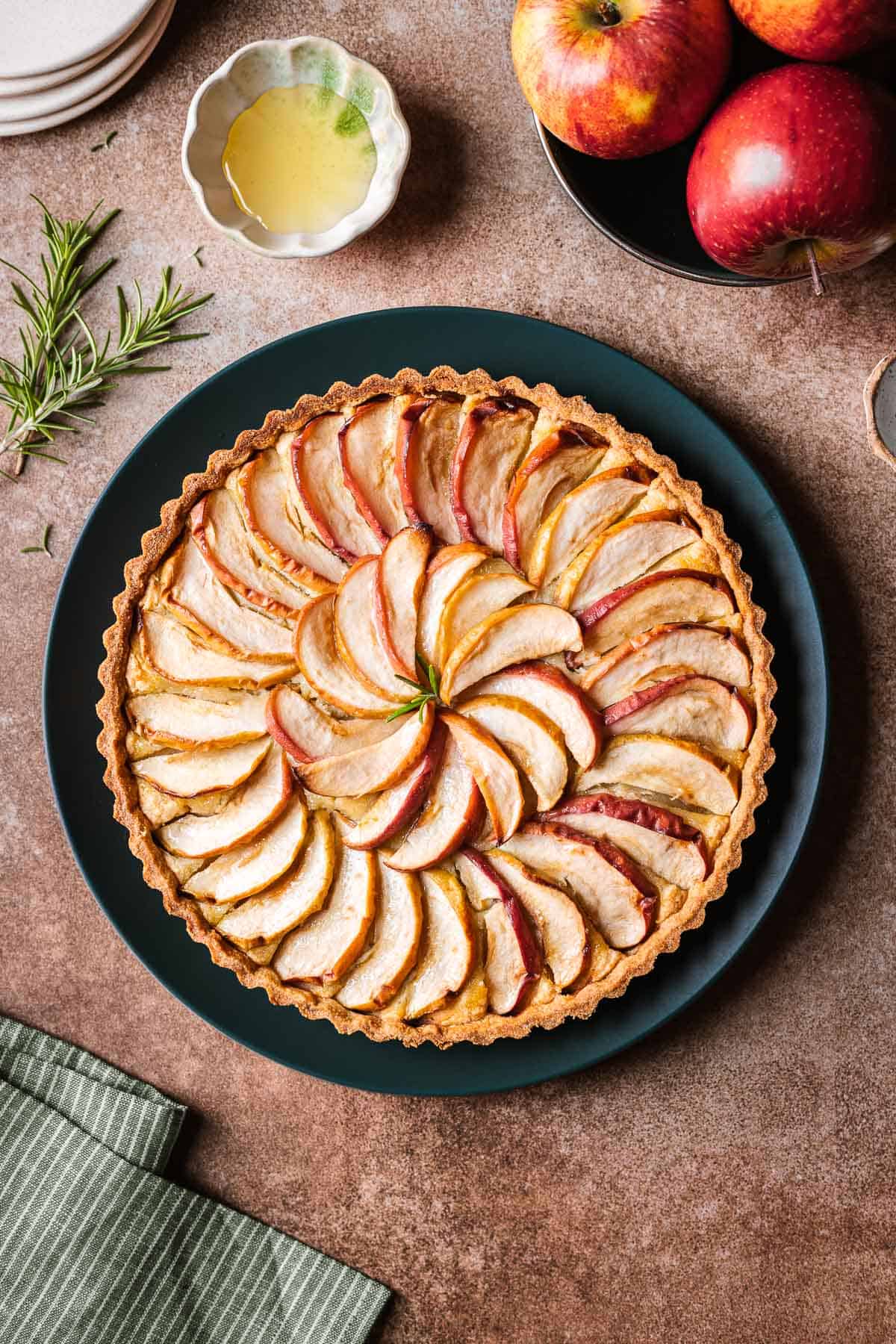 A baked apple frangipane tart on a dark green plate.