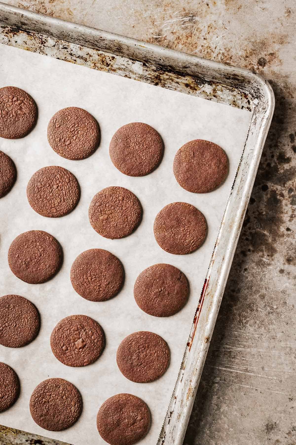 Baked chocolate cookies on a parchment lined baking sheet.
