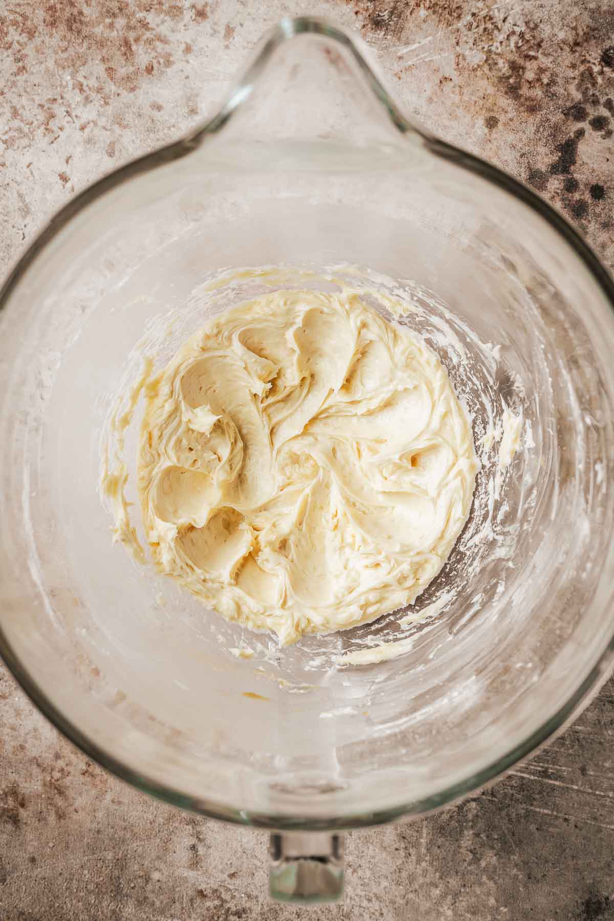 Egg yolks added to butter mixture in a clear glass mixing bowl.