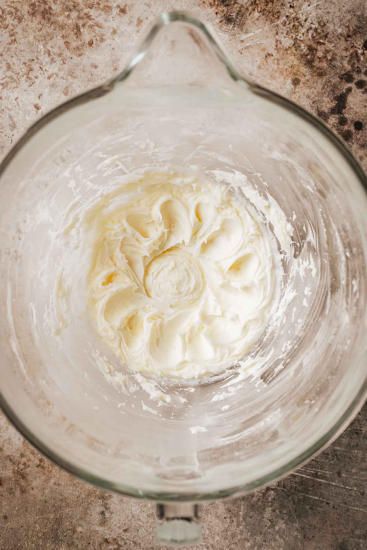 Creamed butter and sugar in a clear glass mixing bowl.