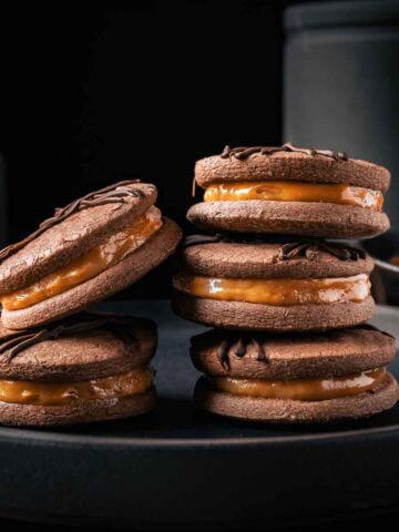 Two stacks of dulce de leche filled chocolate cookies.